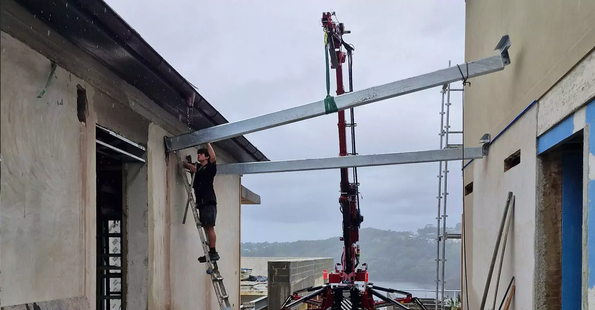 Professional certified operator maneuvering a specialized mini crane on a wet hire project site