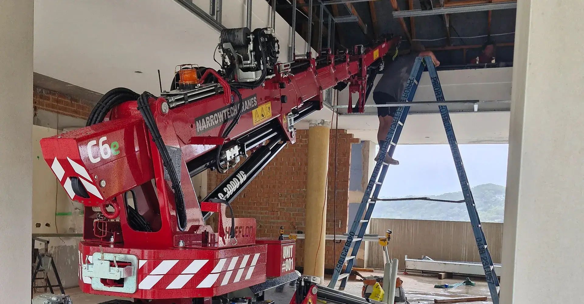 Narrowtech mini crane stationed on a modern boutique construction site with structural steel framework