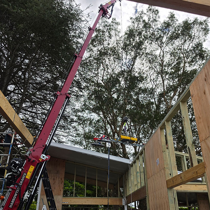 Close-up of a narrow-access mini crawler crane stabilizing legs setup on site